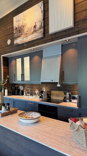 A modern kitchen with dark cabinetry, a central island, and a painting above. - Voss- Myrkdalen|Mountain view |Stunning apartment|Free parking and car charging. (Vestland)