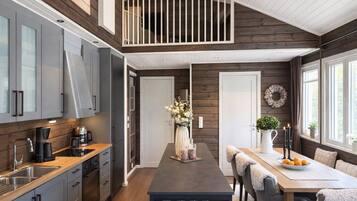 A modern kitchen with a central island, a dining area with a table and chairs, and a loft bedroom with a balcony.