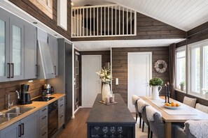 A modern kitchen with a central island, a dining area with a table and chairs, and a loft bedroom with a balcony. - Voss- Myrkdalen|Mountain view |Stunning apartment|Free parking and car charging. (Vestland)