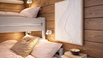 A bunk bed with two pillows, a bedside table with a book, and a framed picture on the wall.