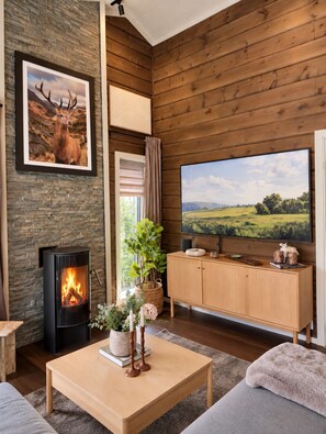 A cozy living room with a fireplace, a television, and a large window. - Voss- Myrkdalen|Mountain view |Stunning apartment|Free parking and car charging. (Vestland)