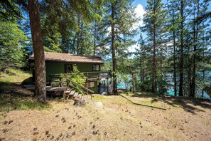 A cabin with a deck, stairs, and a view of a lake surrounded by trees. - Waterfront Sandbar Point w/ Dock Access & Nearby Activities (Hayden)