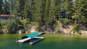 Uma cabana à beira do lago com um cais e rampa coberta para barcos.