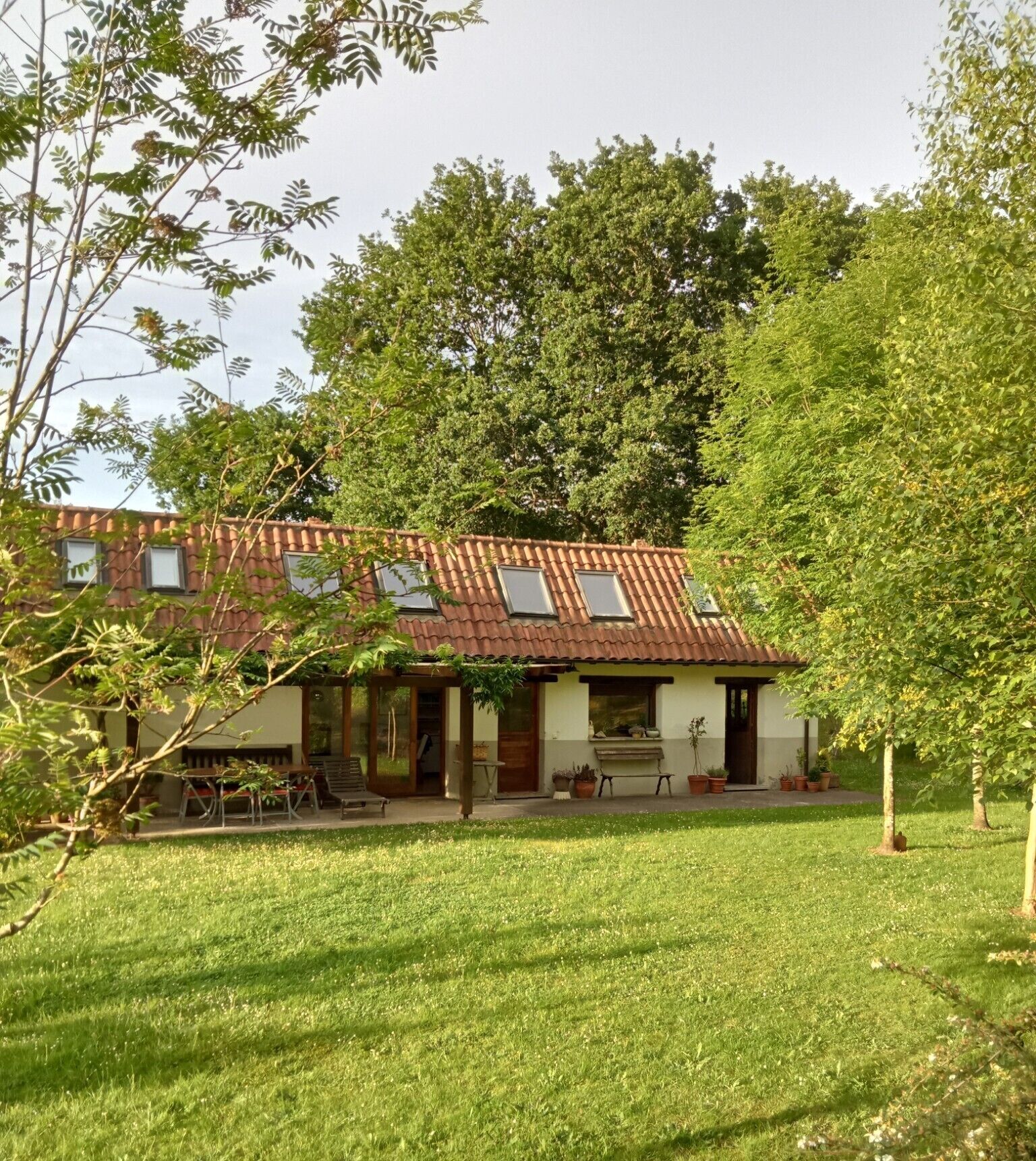 Een huis met een pannendak, een overdekte veranda en een gazon.