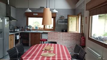 Een keuken met een eethoek, houten balken in het plafond en een rood-wit geruit tafelkleed.