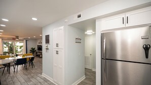 A modern kitchen with stainless steel appliances, a dining area with a table and chairs, and a view of the outdoors. - Relax at our fully renovated peaceful beach condo in Satellite Beach (Satellite Beach)
