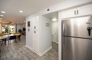 A modern kitchen with stainless steel appliances, a dining area with a table and chairs, and a view of the outdoors. - Relax at our fully renovated peaceful beach condo in Satellite Beach (Satellite Beach)