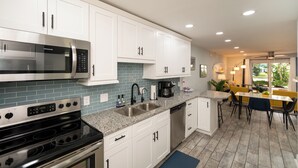 A modern kitchen with white cabinets, a stainless steel microwave, a double oven, and a coffee maker. - Relax at our fully renovated peaceful beach condo in Satellite Beach (Satellite Beach)