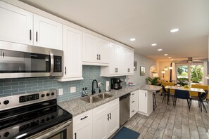 A modern kitchen with white cabinets, a stainless steel microwave, a double oven, and a coffee maker. - Relax at our fully renovated peaceful beach condo in Satellite Beach (Satellite Beach)
