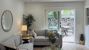 Een woonkamer met een bank, een glazen salontafel, een lamp en uitzicht op een terras.