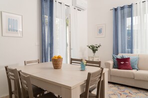 Una habitación con una mesa de comedor, sillas, un sofá y una mesita con un florero.