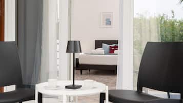 A hotel room with a bed, a table with a lamp, and two chairs.
