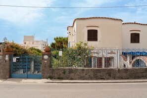Un edificio con pared de piedra, una reja metálica y cielo despejado.