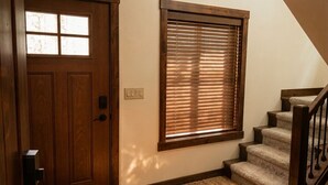 Eine Holztür mit Fenster, einem Lichtschalter und einer Teppichtreppe.