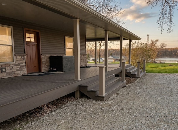 A house with a covered porch, a stone fireplace, and a view of a lake.