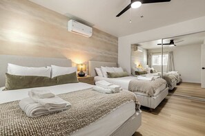 Een hotelkamer met een groot bed, een nachtkastje met een lamp, een plafondventilator en een grote spiegel.