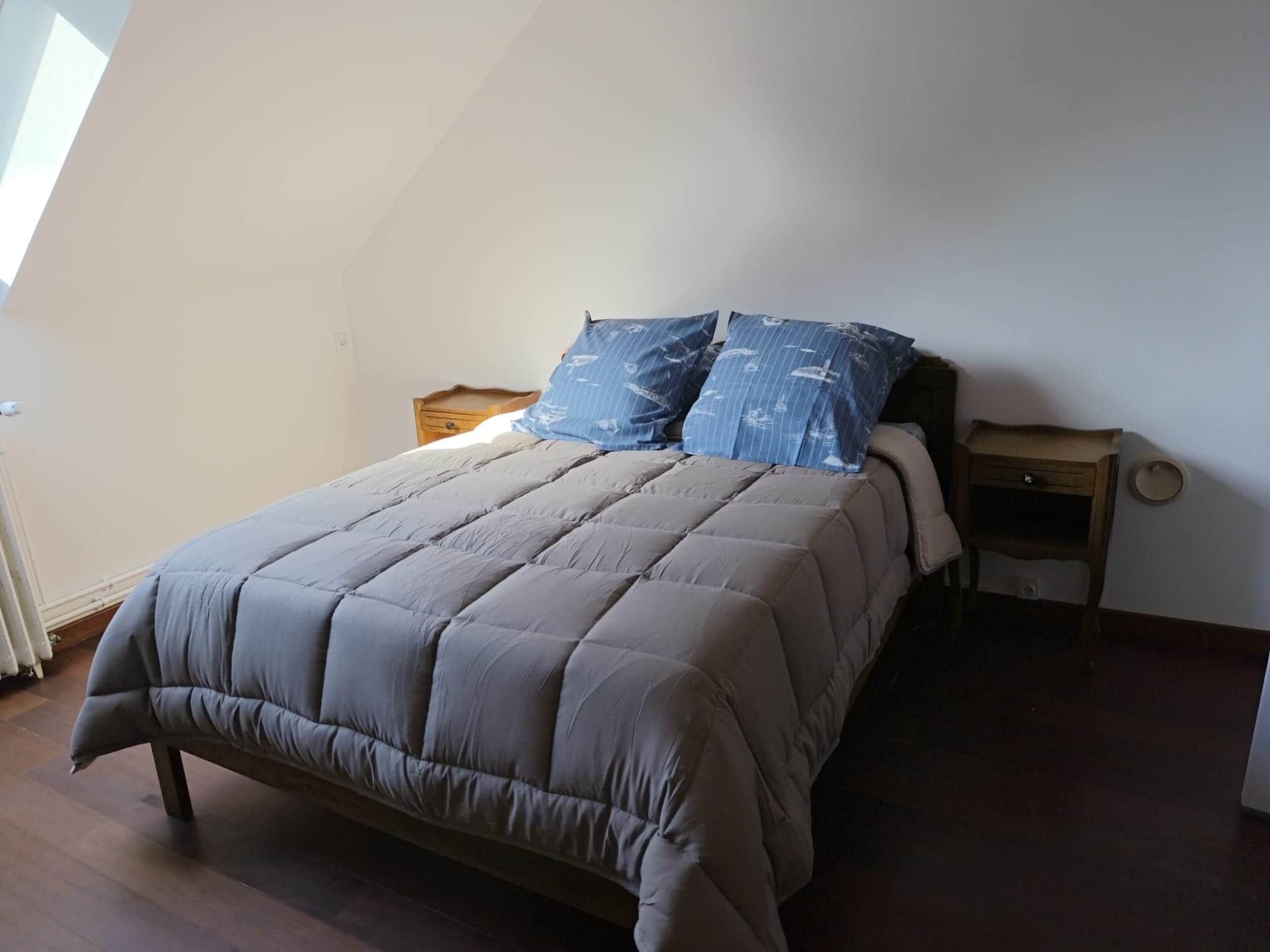 A bedroom with a bed, two nightstands, and a window.