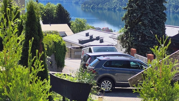 A car parked in a driveway with a view of a lake and mountains in the background. - Apartment Sunshine lake and mountain view with 60 sqm terrace facing south and east (Millstatt)