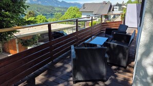 A balcony with wicker furniture, a view of a mountain, and a parking area. - Apartment Sunshine lake and mountain view with 60 sqm terrace facing south and east (Millstatt)