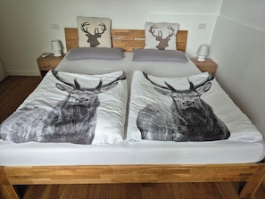 Una cama doble con dos almohadas, cada una con la silueta de un ciervo.