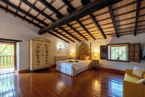 A bedroom with a wooden ceiling, a bed with white bedding, a nightstand, a wardrobe, and a window with a view.