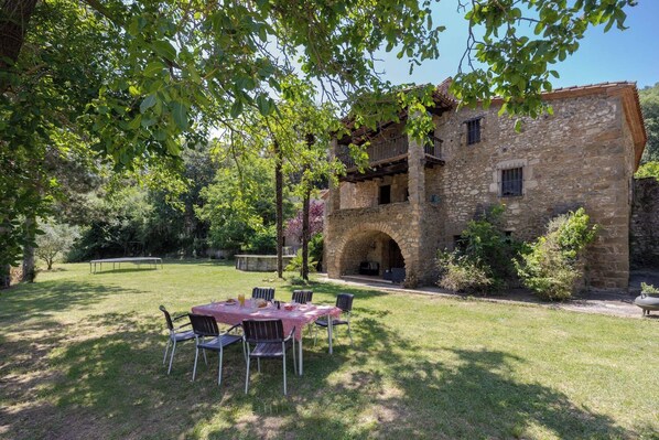 A stone building with a covered outdoor seating area and a trampoline.