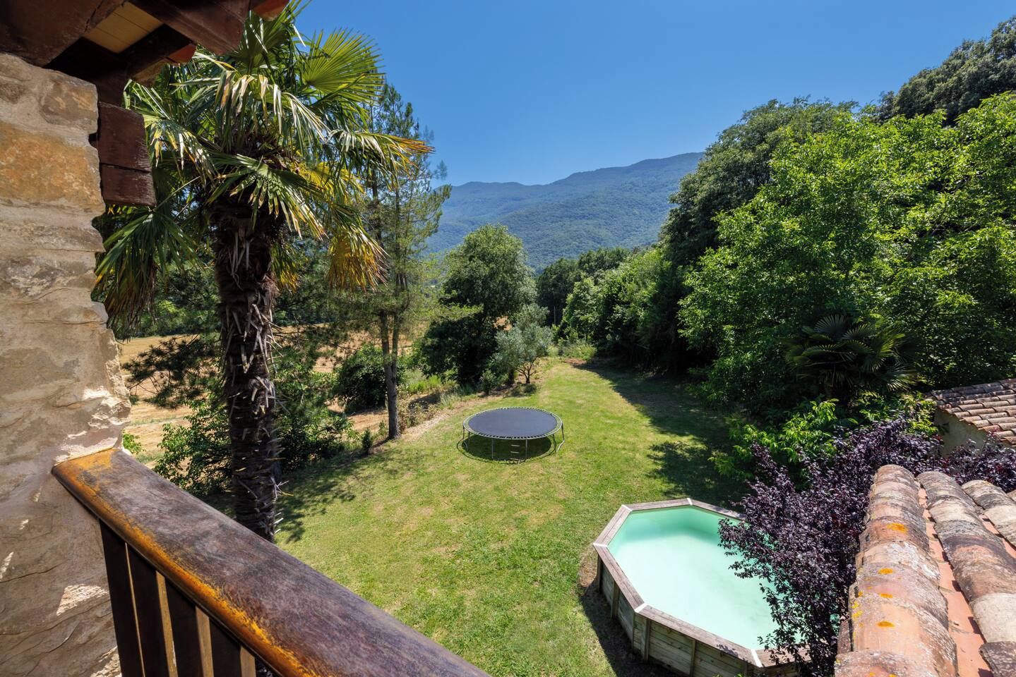 Un jardin avec un trampoline, une petite piscine et une vue sur une chaîne de montagnes.