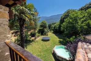 Un jardin avec un trampoline, une petite piscine et une vue sur une chaîne de montagnes.