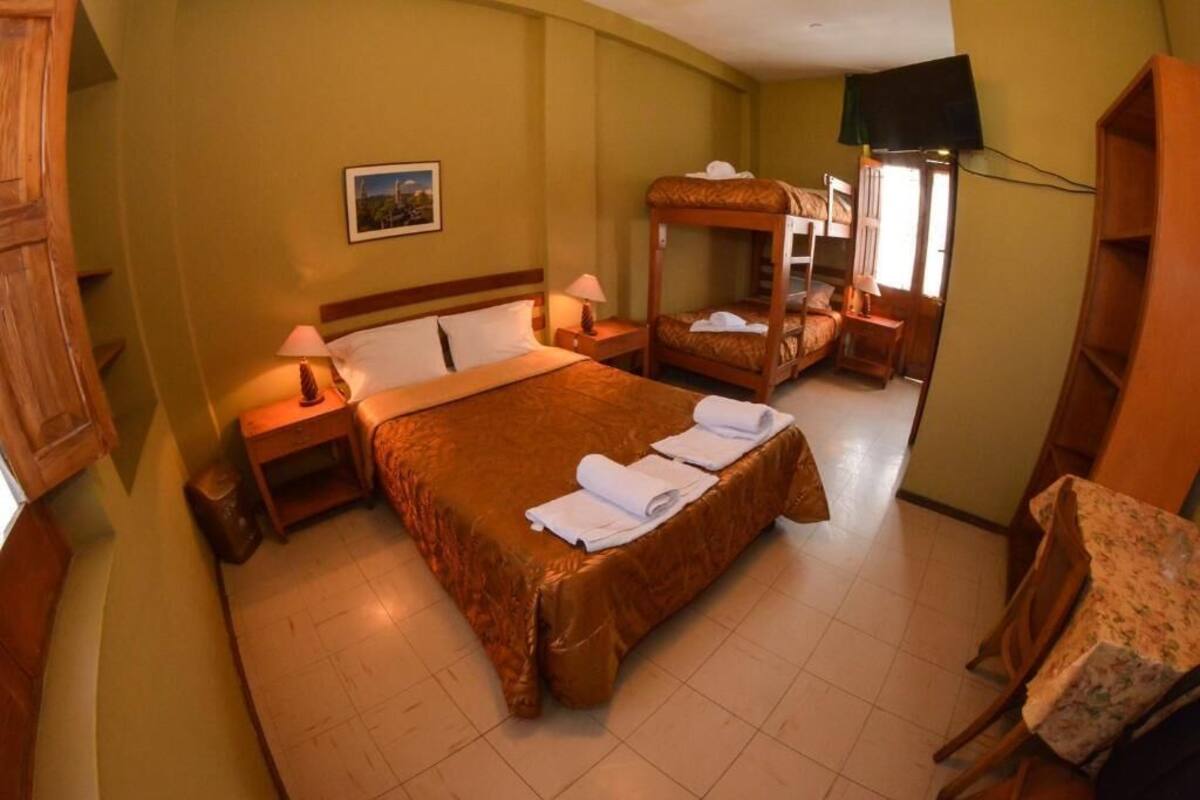 Una habitación de hotel con una cama grande, una cama más pequeña, un escritorio y una silla.