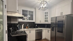 Uma cozinha moderna com armários brancos, eletrodomésticos de aço inoxidável e piso de madeira.