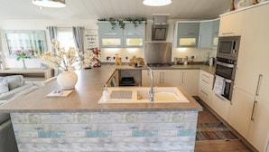 Una cocina moderna con una isla central, electrodomésticos de acero inoxidable y un comedor con sofá y mesa.