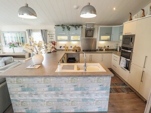 A modern kitchen with a central island, stainless steel appliances, and a dining area with a sofa and table.