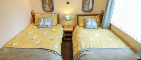 A twin room with two beds, each with goose-patterned bedding, a nightstand with a lamp, and two wall-mounted mirrors.