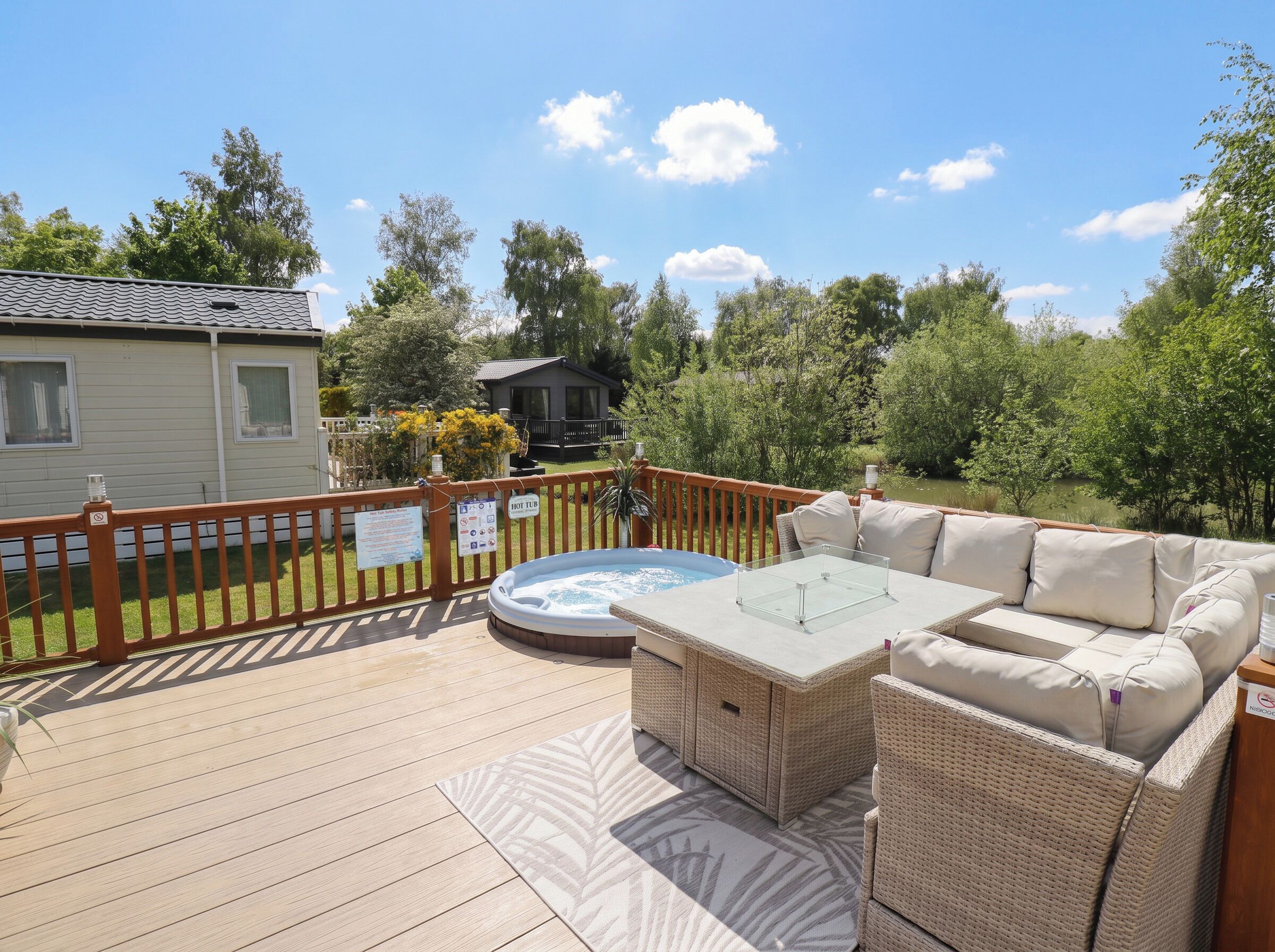 A deck with a hot tub, wicker furniture, and a view of a lake.