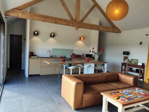 A modern living space with a kitchen, a brown leather sofa, and a coffee table with a colorful geometric design. - New house in the heart of the Loire castles - sleeps 4 (Chinon)