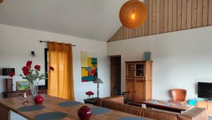 A modern kitchen with a wooden island, a dining area with a sofa, and a TV. - New house in the heart of the Loire castles - sleeps 4 (Chinon)
