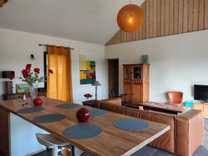 A modern kitchen with a wooden island, a dining area with a sofa, and a TV. - New house in the heart of the Loire castles - sleeps 4 (Chinon)