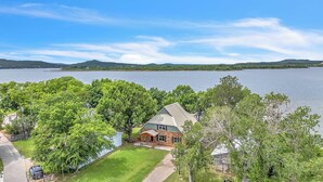 A house with a stone exterior, a covered porch, and a view of a lake. - Swim Platform + Lakefront Double Deck + Walk to Marina + Near Rocker B (Graford)