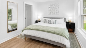 A bedroom with a bed, bedside tables, a ceiling fan, a wall-mounted light fixture, and a window. - Swim Platform + Lakefront Double Deck + Walk to Marina + Near Rocker B (Graford)