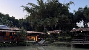 A tranquil riverside setting with wooden structures, a boat, and lush greenery.