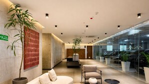 Een moderne lobby met een bank, stoelen, een receptiebalie en een glazen wand met auto's.