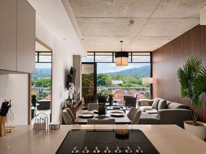 Ein modernes Wohnzimmer mit Essbereich, großen Fenstern und Blick auf eine Stadtlandschaft.