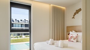Habitación de hotel con cama, ventana grande, vista a una piscina y un edificio moderno en el exterior.