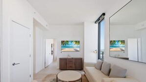 Un soggiorno moderno con un divano, un tavolino, un mobile e un quadro raffigurante una spiaggia.