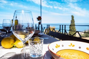 Una mesa con una copa de vino, un vaso de agua, limones y un plato con un diseño amarillo.