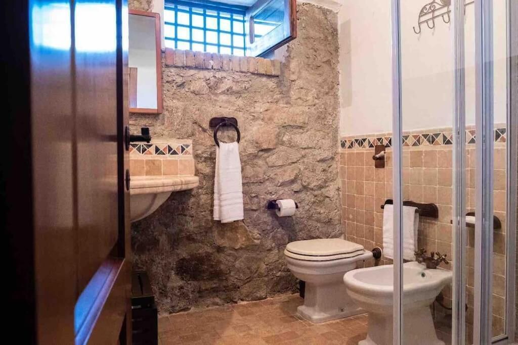 Un baño con pared de piedra, lavabo, inodoro y bidé.