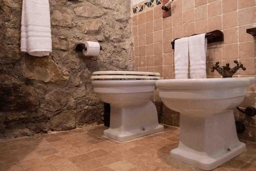 Et badeværelse med to toiletter, toiletpapir og et håndklædestativ.