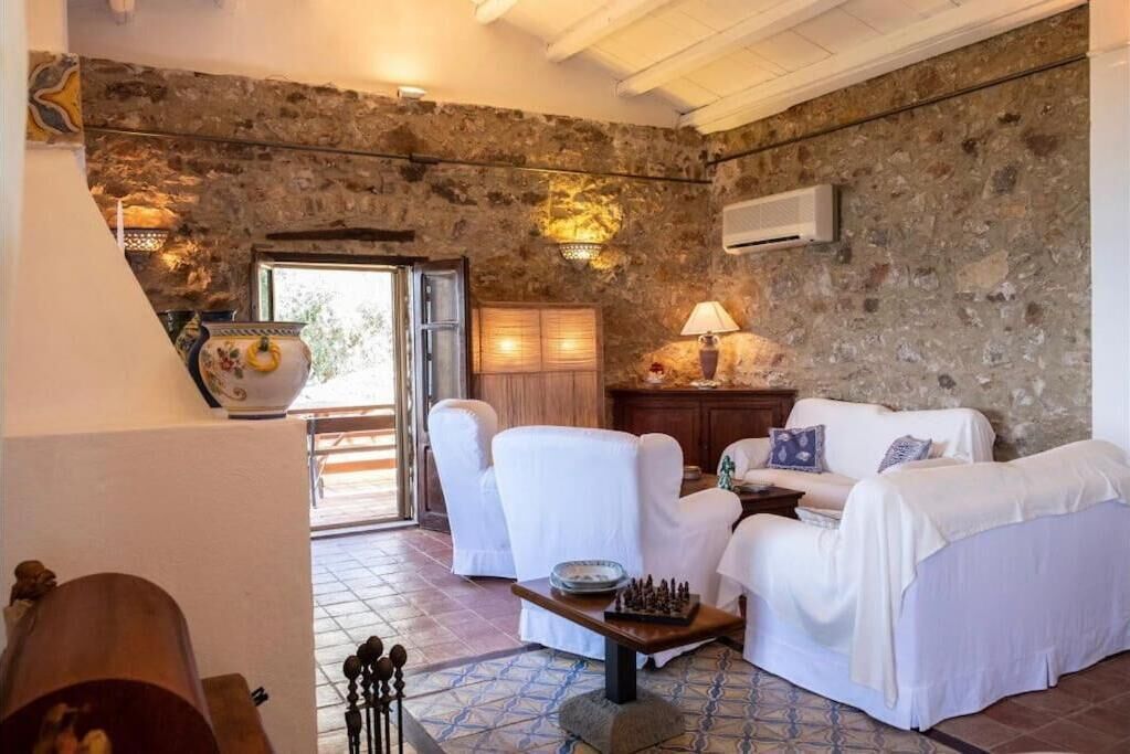 A stone-walled room with white furniture, a chessboard, and a lamp.