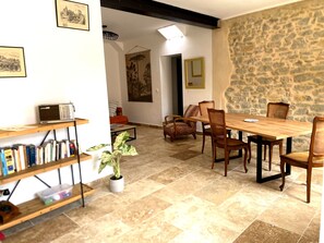 A dining area with a stone wall, wooden table, and chairs. - Single-storey house in the Capucins district - near Paicherou swimming pool and Cité (Carcassonne)