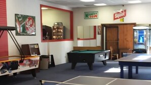 A room with a pool table, a ping pong table, and a billiards table.